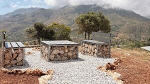 Un espacio de estar al aire libre rústico con bancos de piedra y un camino de grava, con vistas a un paisaje montañoso.