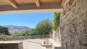Una habitación con paredes de piedra, techo de madera, un banco de piedra y vistas a la montaña.