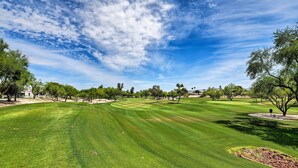 A well-maintained golf course with a clear sky, trees, and a small building in the distance. - Scottsdale Condo w/ Patio, Pool & Hot Tub! (Scottsdale)