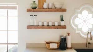 A kitchen with wooden shelves holding kitchenware, a basket, a coffee maker, and a sink. - Scottsdale Condo w/ Patio, Pool & Hot Tub! (Scottsdale)