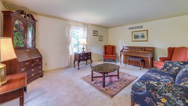 A living room with a wooden cabinet, a glass coffee table, a sofa, a chair, and a piano. - Family-friendly West Chester Twp Home w/ Pool! (West Chester)