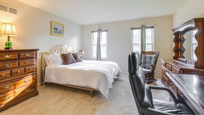 A bedroom with a bed, dresser, chair, and a large mirror. - Family-friendly West Chester Twp Home w/ Pool! (West Chester)