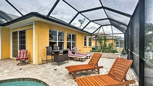 A covered outdoor area with a pool, lounge chairs, and a dining set. - Cape Coral House w/ Private Dock, Pool & Bar! (Cape Coral)