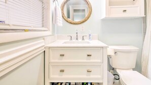A bathroom with a white sink, two drawers, a mirror, and a toilet.