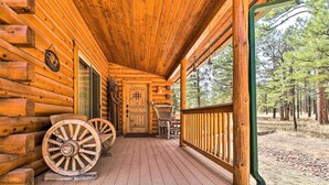 Una cabaña de troncos con un porche de madera, una puerta y dos ruedas de madera grandes.