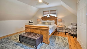 Une chambre à coucher avec un lit en bois, un ventilateur de plafond, un banc, une chaise et une table de chevet.