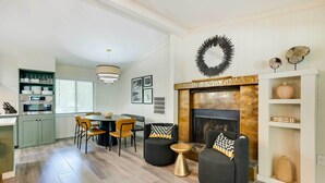 A modern living room with a fireplace, a dining area with a round table and chairs, and a kitchen with built-in shelves. - Riverfront Cottage in Homosassa: 'chateau Relaxo' (Homosassa)