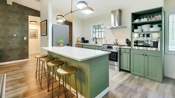 A modern kitchen with a central island, bar stools, a built-in oven, and a green cabinetry. - Riverfront Cottage in Homosassa: 'chateau Relaxo' (Homosassa)
