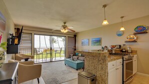 A kitchen with a granite countertop, stainless steel appliances, and a dining area with a table and chairs. - Molokai Shores Resort Condo w/ Pool & Views! (Kaunakakai)