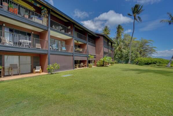 A two-story hotel with balconies, outdoor seating, and a well-maintained lawn. - Molokai Shores Resort Condo w/ Pool & Views! (Kaunakakai)