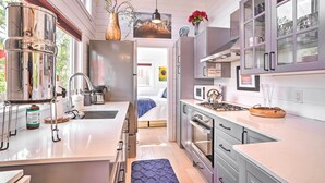 Une cuisine moderne dotée d’appareils électroménagers en acier inoxydable, d’un grand îlot central et donnant sur la chambre adjacente.