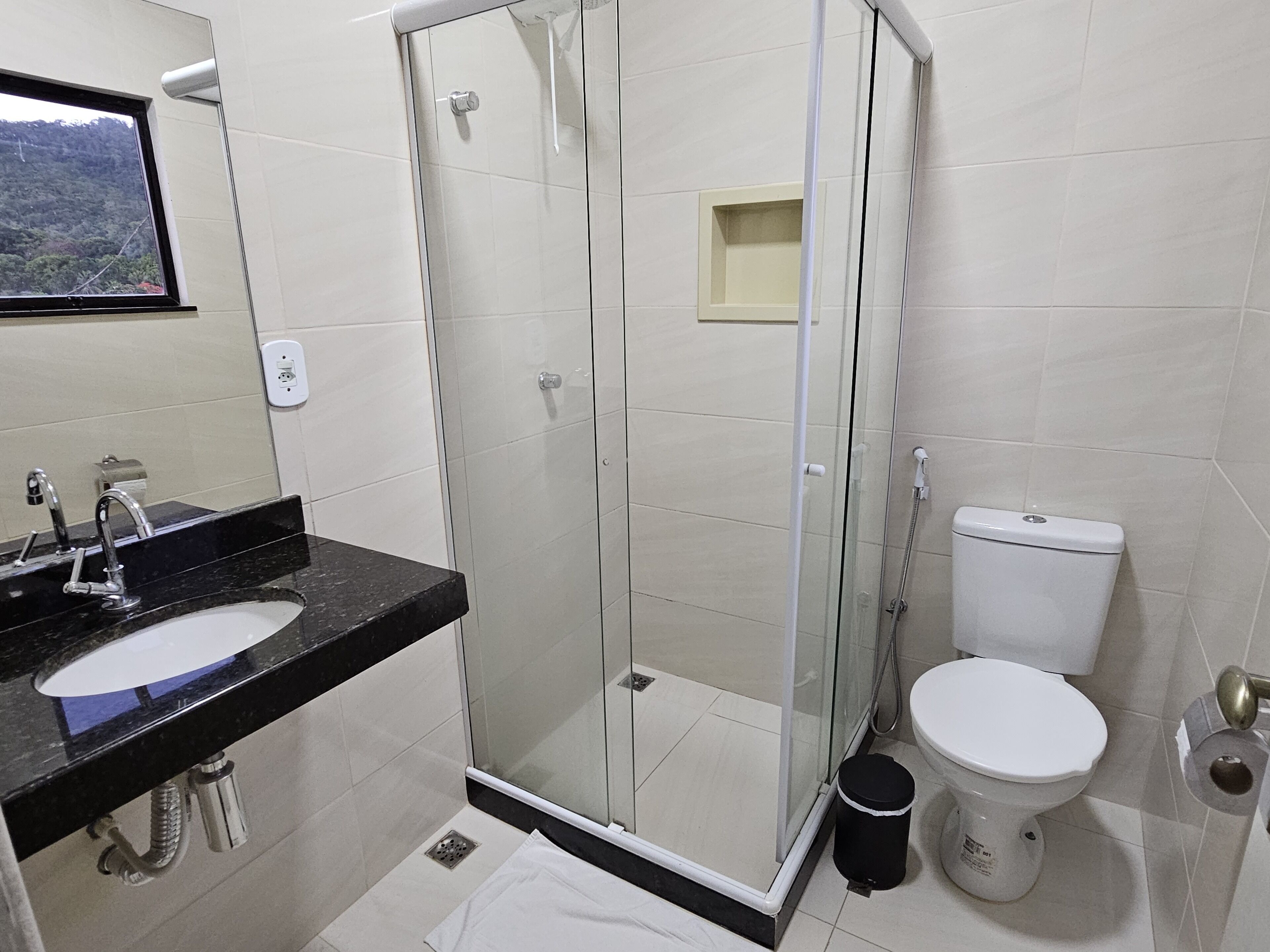 A modern bathroom with a glass-enclosed shower, a sink with a mirror, and a toilet.