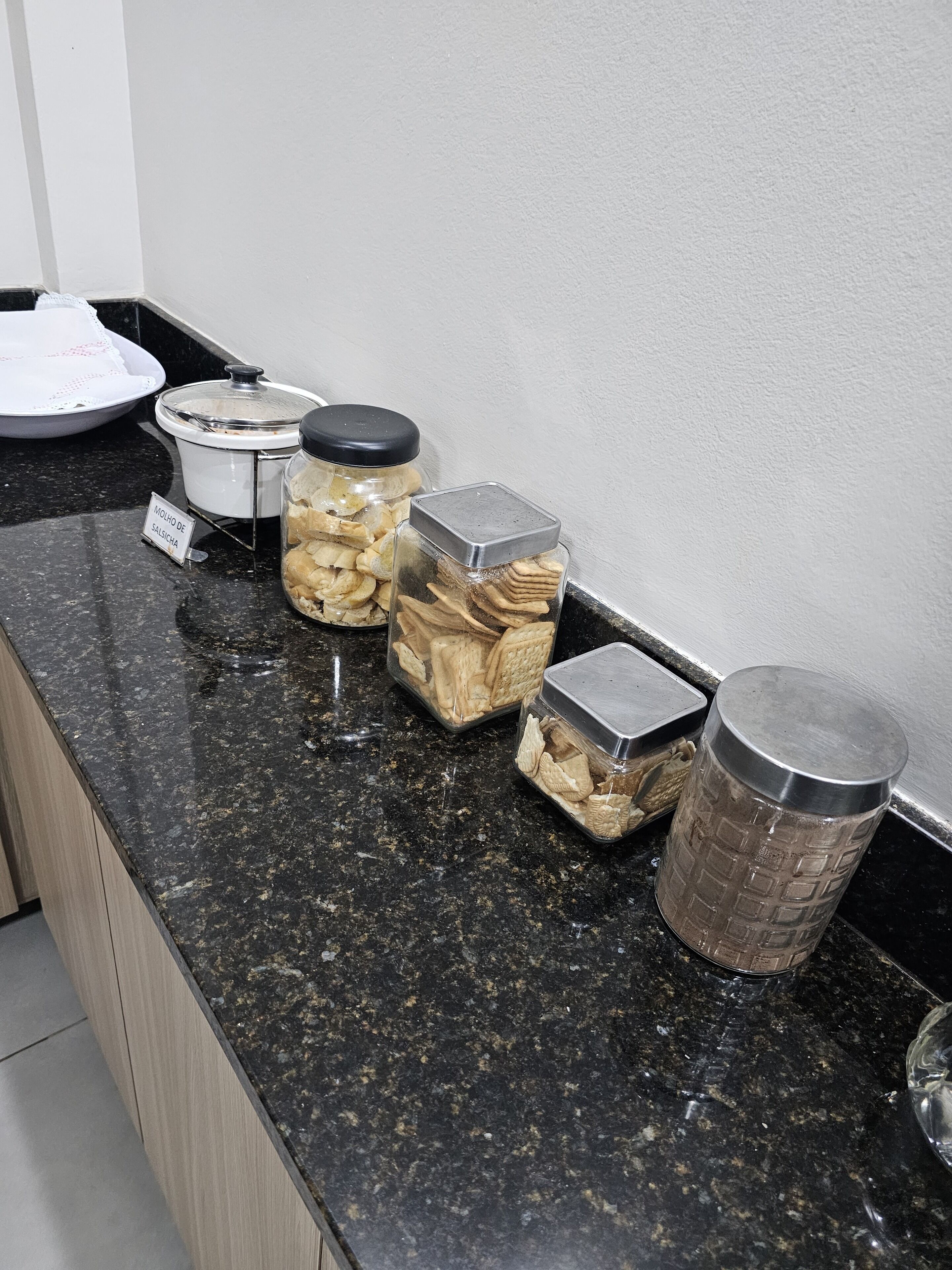 A kitchen counter with jars of snacks and a metal container.