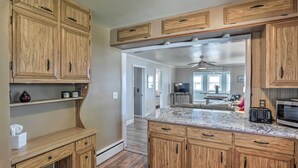 A kitchen with wooden cabinets, a marble countertop, and a microwave. - Lakefront Cottage w/ Fishing & Private Yard! (Port Clinton)