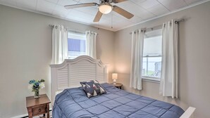 A bedroom with a bed, a nightstand, a ceiling fan, and a window with curtains. - Lakefront Cottage w/ Fishing & Private Yard! (Port Clinton)