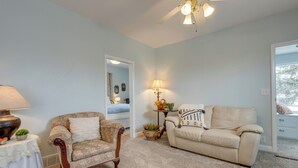 A living room with a beige sofa, a patterned armchair, a small table with a lamp, and a ceiling fan. - Burley Home w/ Playground - 1 Mi to Golf Course! (Burley)