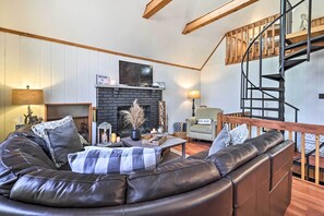 Una sala de estar acogedora con chimenea, sofá de cuero y una escalera de madera.