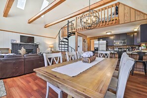 Un salón amplio con una mesa de comedor de madera, una chimenea y una cocina moderna con horno y microondas integrados.