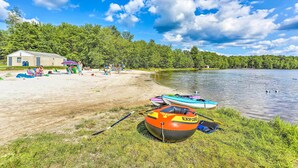 A lakeside setting with a small dock, a boat, and an inflatable raft. - Fire Pit & Grill: 'woodside Nest' in Pocono Lake! (Pocono Lake)