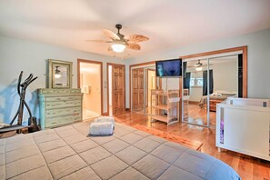 Une chambre à coucher comprenant un lit, une commode, un ventilateur de plafond et un téléviseur.