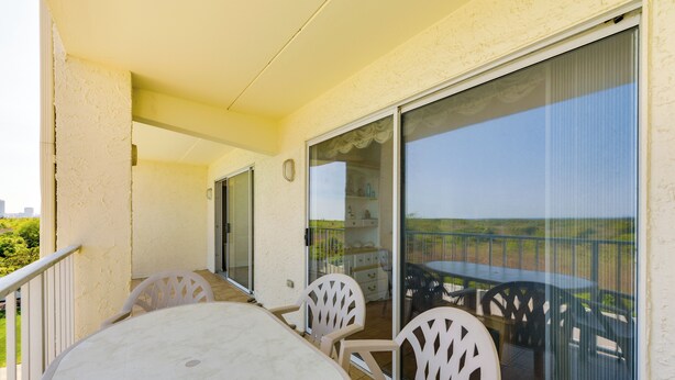 A balcony with a table and chairs, a sliding glass door, and a view of the landscape. - Atlantic City Area Vacation Rental w/ Pool Access! (Brigantine)