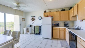 A kitchen with a refrigerator, microwave, and wooden cabinets. There is a dining table with chairs and a ceiling fan. - Atlantic City Area Vacation Rental w/ Pool Access! (Brigantine)