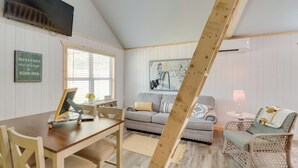 Un salon chaleureux avec une table à manger en bois, un canapé et un fauteuil en osier.