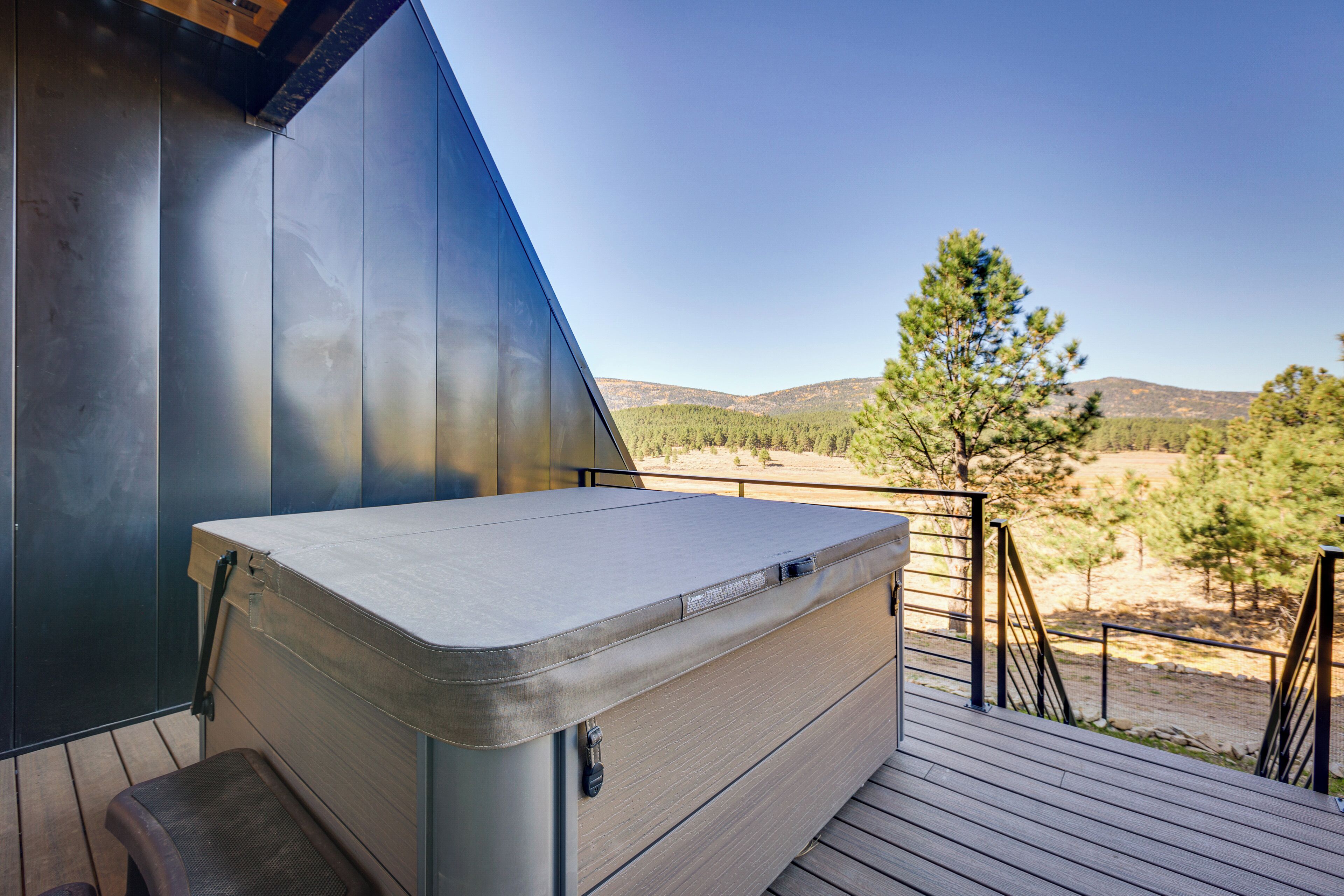 A wooden deck with a large mattress on it, overlooking a mountainous landscape.