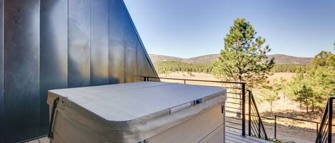 A wooden deck with a large mattress on it, overlooking a mountainous landscape.
