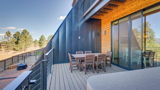 A modern outdoor deck with a dining table and chairs, a wooden railing, and a view of the surrounding landscape. - Angel Fire Home w/ Hot Tub < 1 Mi to Ski Slopes! (Angel Fire)