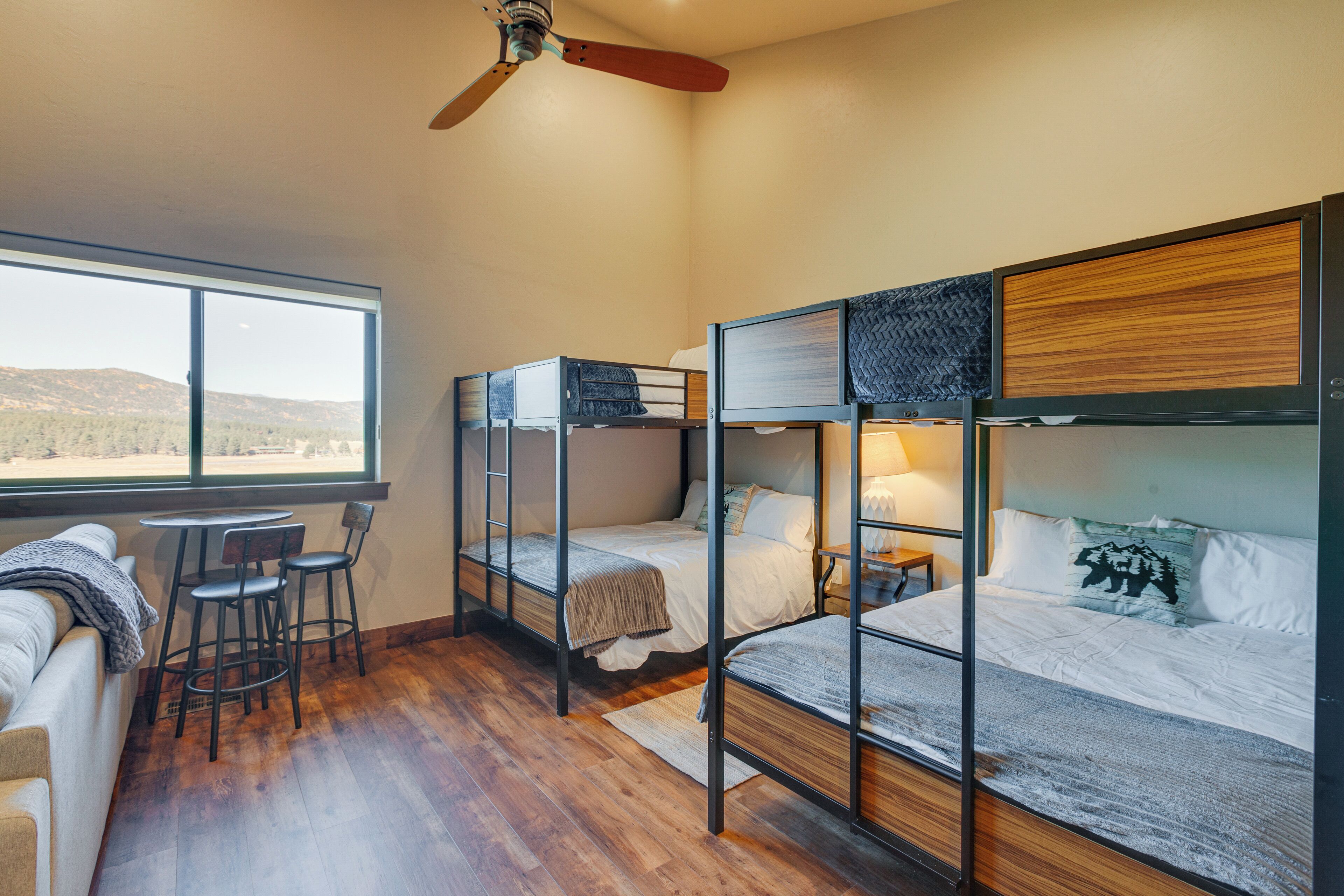 A room with bunk beds, a sofa, and a table with chairs.