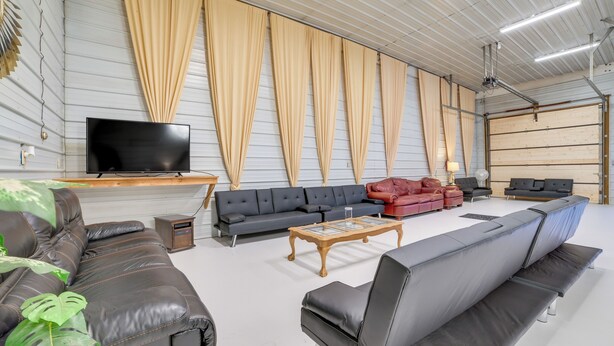 Un salón amplio con un gran sofá, un televisor y cortinas en las paredes.