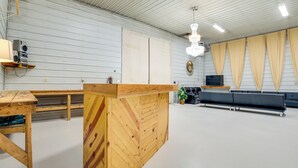 Una habitación amplia con un mostrador de recepción de madera, un sofá negro y un ventanal con cortinas.