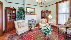 Un salon traditionnel avec une cheminée, deux fauteuils, une table basse et un lustre.