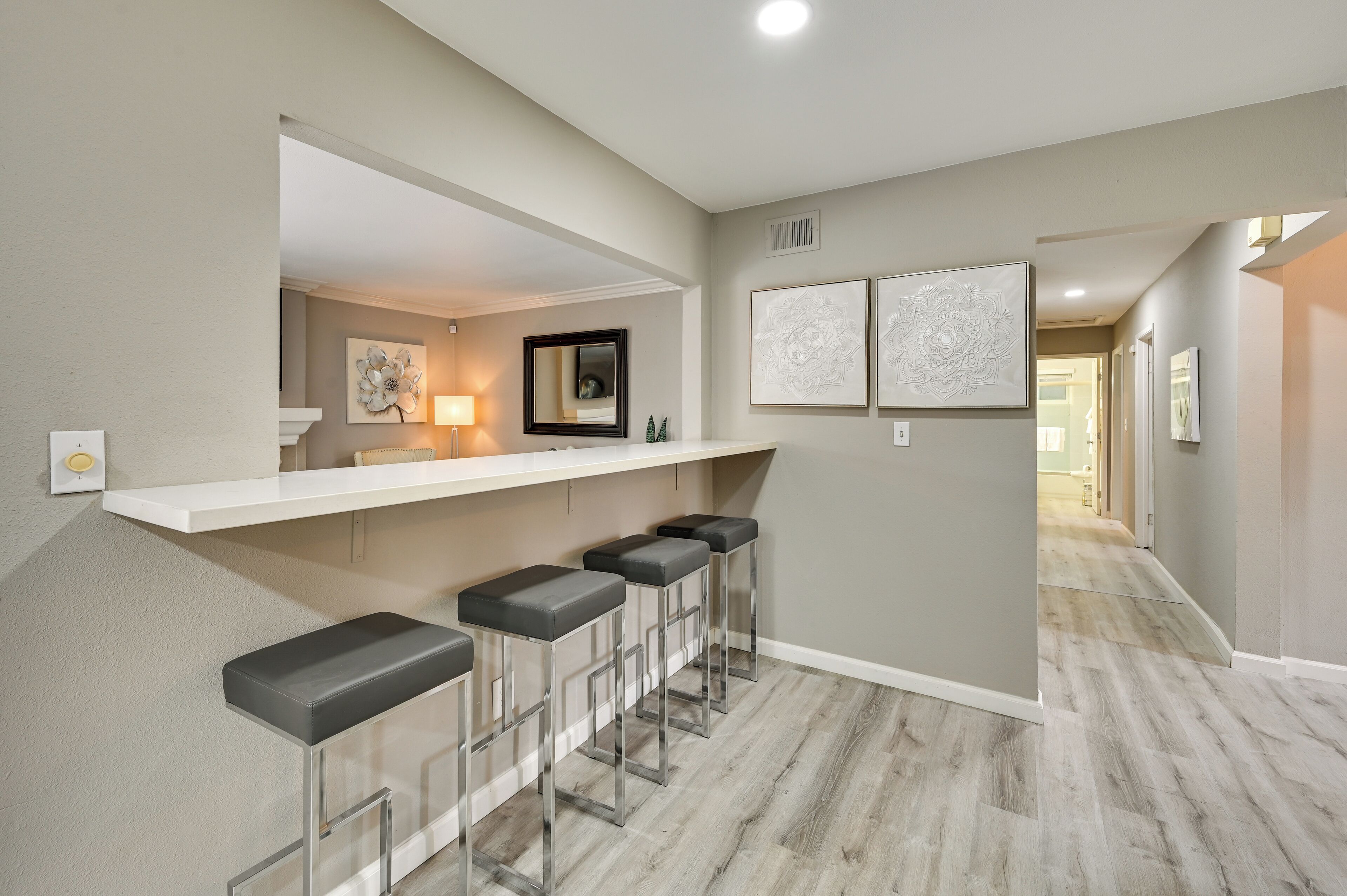 Una cocina moderna con encimera blanca y cuatro taburetes de bar.