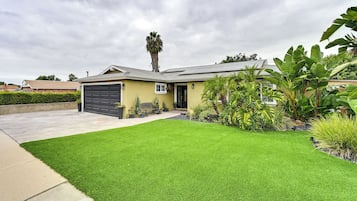 Stunning home with a modern design, featuring a well-maintained lawn and tropical plants.