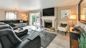 Una sala de estar moderna con chimenea, televisor montado encima y un espacio de asientos cómodo con sofá y sillones.