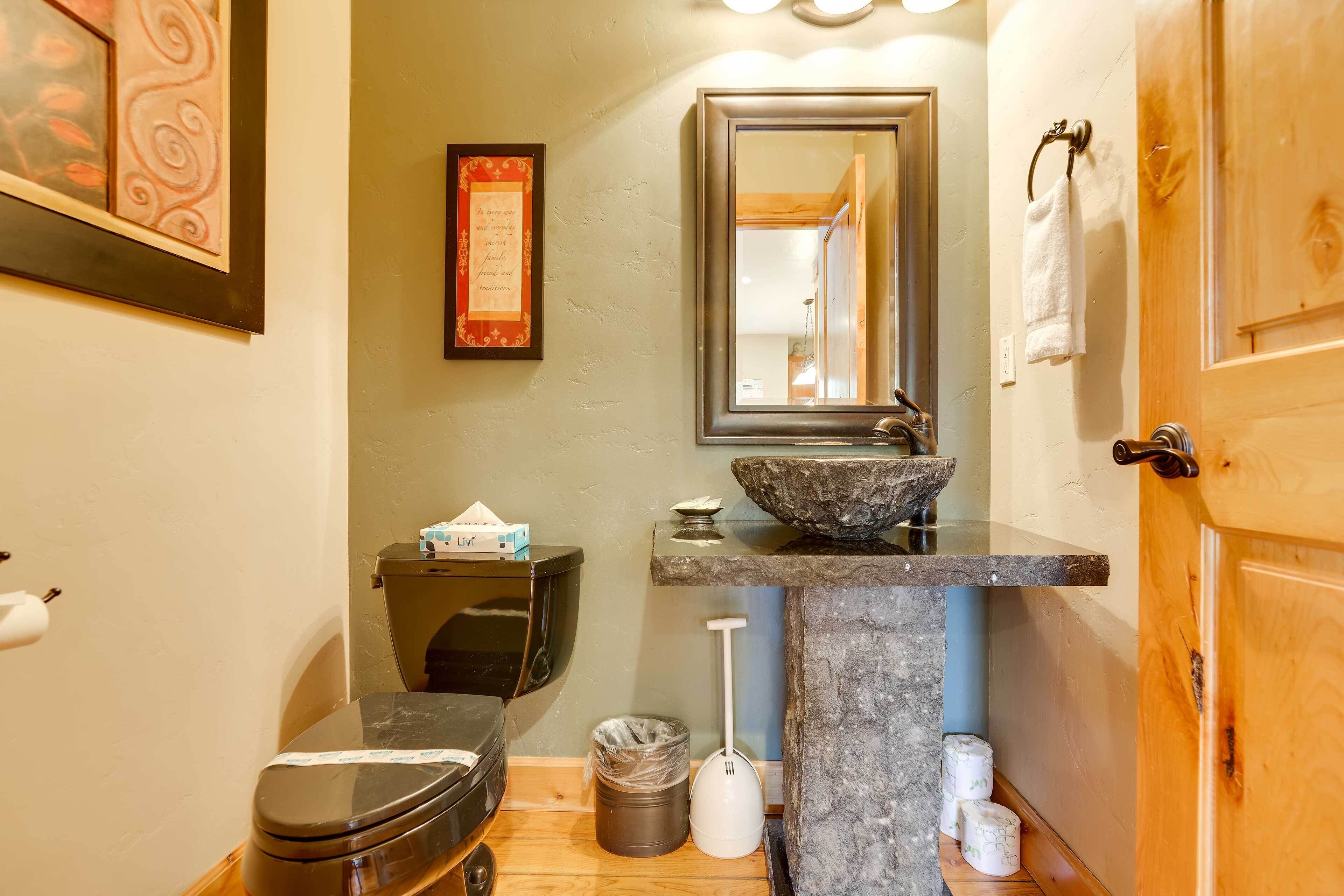 A bathroom with a toilet, sink, mirror, and towel rack.