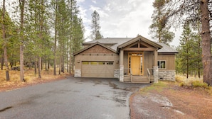 A two-story house with a garage, surrounded by tall pine trees. - Sunriver Group Getaway: Explore Deschutes Forest! (Bend)
