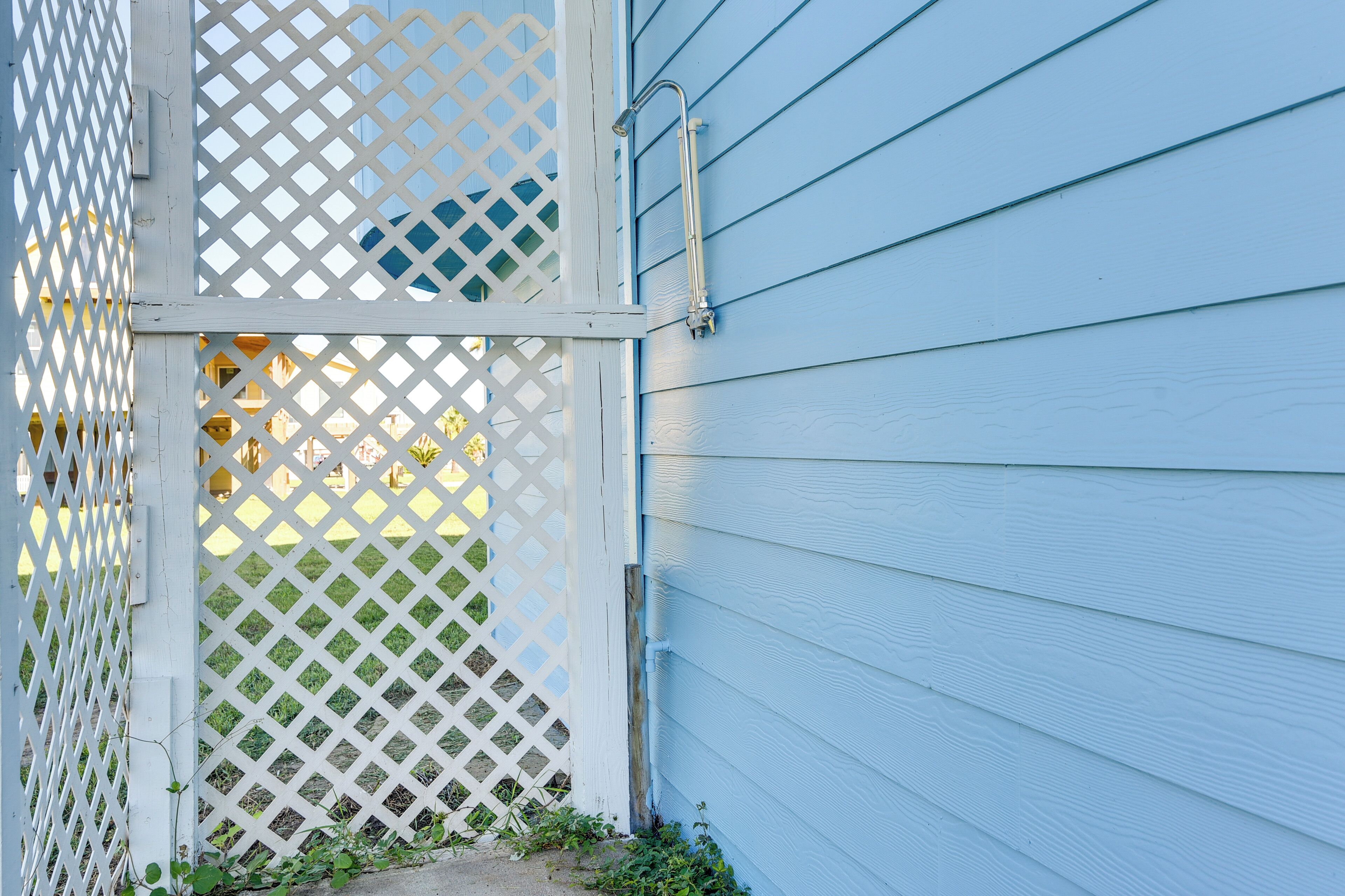 A white lattice gate and a metal handrail attached to a blue house siding.