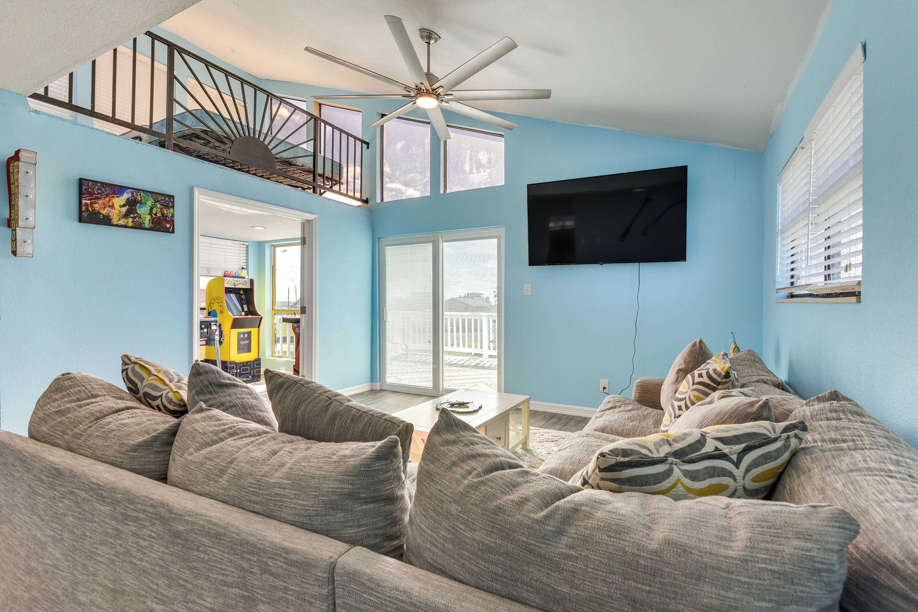 A living room with a gray sofa, a ceiling fan, a TV, and a staircase leading to an upper level.
