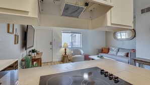 Une cuisine moderne dotée d’un îlot central, un coin repas avec une table et des chaises, un canapé et une fenêtre laissant entrer la lumière naturelle.