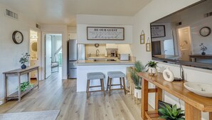 Une cuisine moderne dotée d’un îlot central, de tabourets de bar, d  ’une table à manger en bois et d’un grand téléviseur à écran plat.