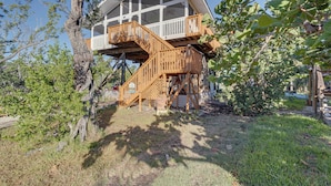 A treehouse with a wooden staircase and a balcony.