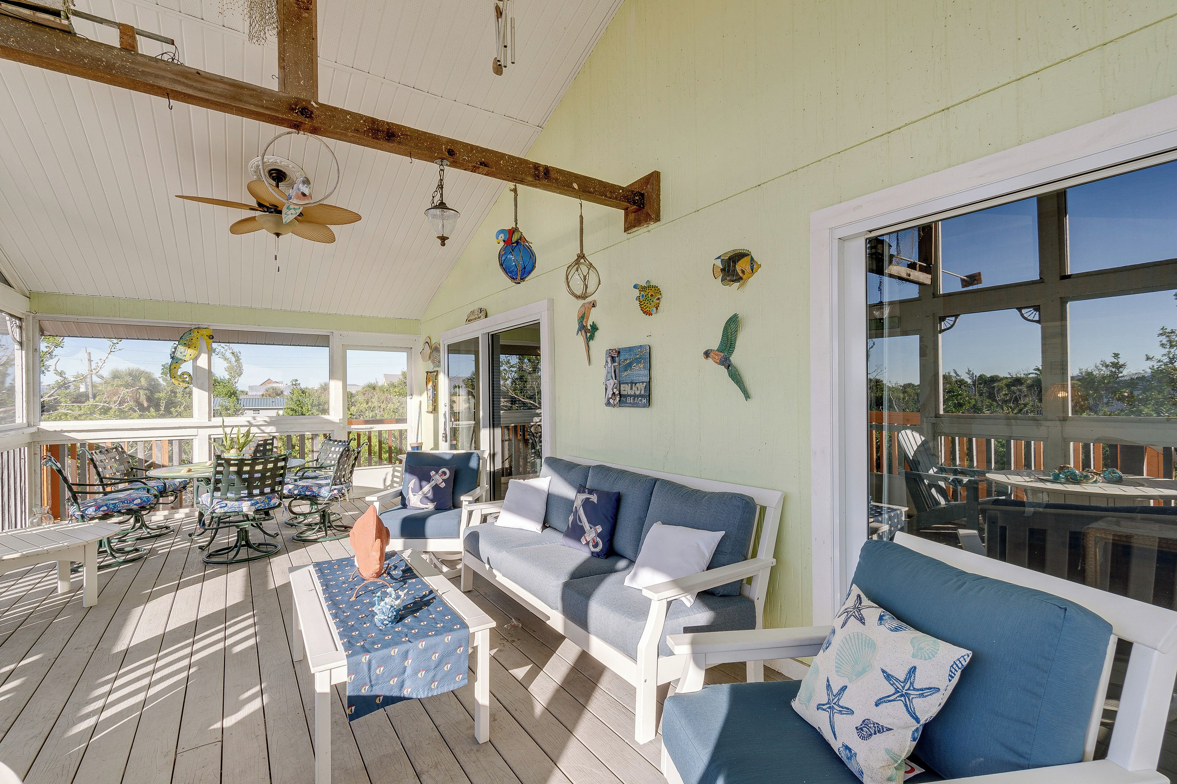 A covered outdoor seating area with a white sofa, blue cushions, and a table with a blue tablecloth.