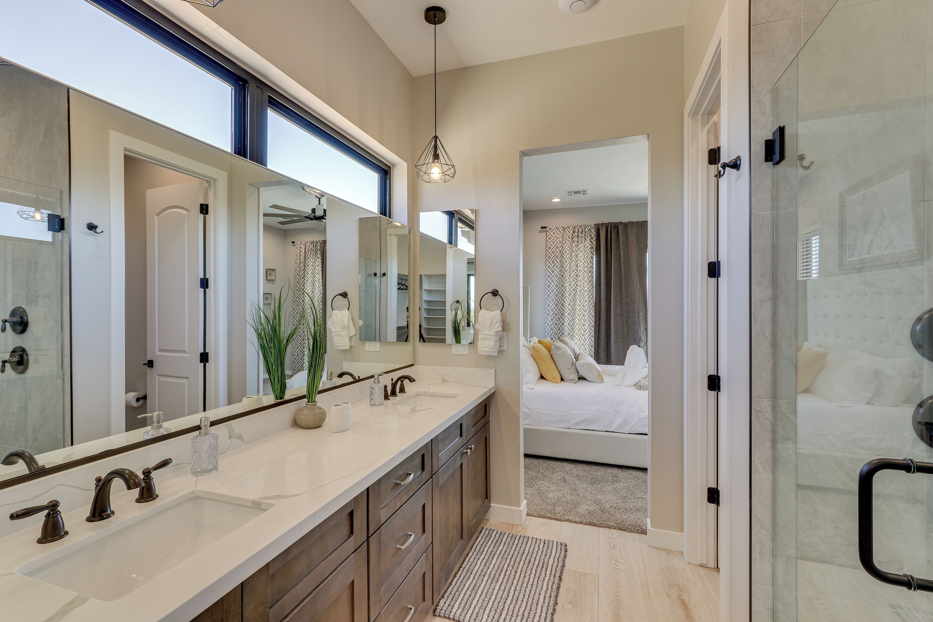 A modern bathroom with a large mirror, dual sinks, and a walk-in shower.