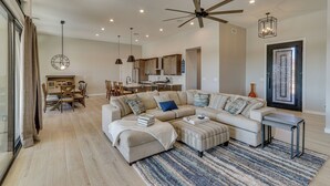 Un salón espacioso con un sofá modular, una zona de comedor y una cocina al fondo.
