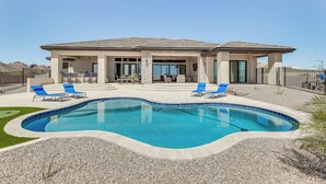 Una casa moderna con piscina, dos sillones de descanso y un patio.