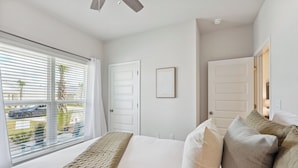 Un dormitorio con una cama grande, paredes blancas y una ventana con persianas.