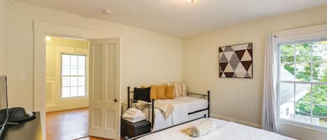Una camera da letto con un letto, una scrivania, una sedia, una finestra e una porta che conduce a un'altra stanza.
